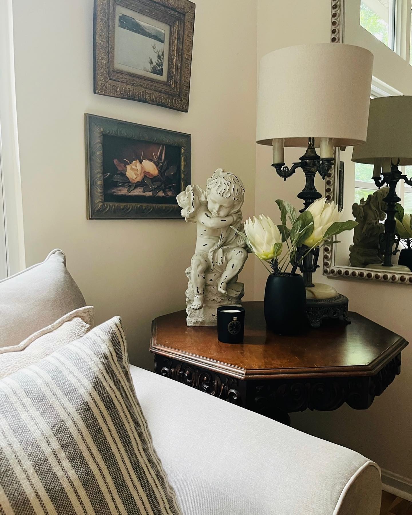A comfortable sitting corner with vintage art and layered furnishings styled by Kristin Saunders